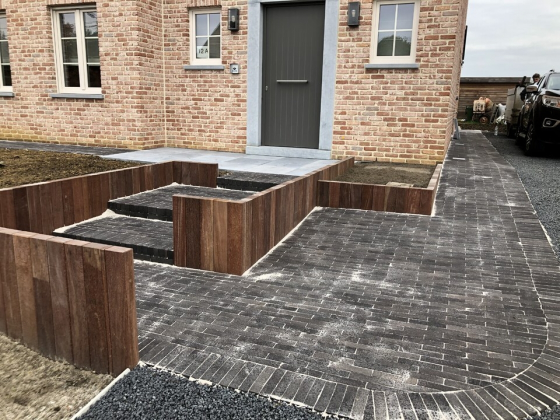 Trede met houten keermuren als opstap bij de voordeur.